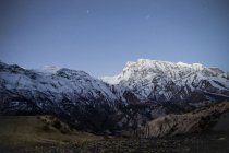Alti ripidi pendii di montagne coperte di neve situate nella catena montuosa dell'Himalaya sotto il cielo colorato in Nepal — Foto stock