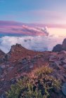 Nascer do sol em poderosos picos de montanha em meio a nuvens brancas grossas e macias e, no fundo, a erupção de um vulcão. Erupção vulcânica Cumbre Vieja nas Ilhas Canárias de La Palma, Espanha, 2021 — Fotografia de Stock