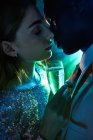 Vue latérale du couple de cultures avec verre de champagne dans le moment de baiser contre un rayon lumineux brillant en se regardant pendant la fête — Photo de stock
