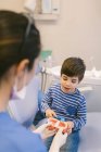 Kieferorthopädin lehrt Patientin mit Zahnbürste Zähne nach Kiefermodell in Zahnklinik — Stockfoto