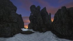 Vista panorámica del turista con antorcha en tierra arenosa entre montañas agitadas bajo el cielo nublado con estrellas al atardecer - foto de stock
