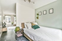 Сучасна спальня і інтер'єр вітальні з подушками на ковдрі між горщиками рослин в будинку з плиткою підлоги — стокове фото