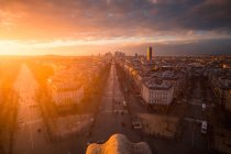 Drone vista de fachadas de casas urbanas y carreteras con transporte bajo el cielo nublado brillante al atardecer en París Francia - foto de stock