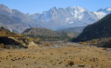 Высокие крутые склоны гор, покрытые снегом, расположенные в долине Гималаев под красочным небом в Непале — стоковое фото