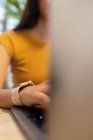 Uma jovem empresária irreconhecível sentada à mesa e a navegar no netbook enquanto trabalhava num local de trabalho moderno — Fotografia de Stock