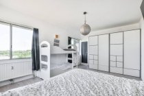 Вид з ліжка інтер'єру сучасної спальні з білими меблями і чорними шторами в квартирі, спроектованій в мінімальному стилі — стокове фото