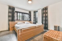 Сучасний інтер'єр спальні з ліжком з подушками під світиться лампа на стелі в квартирі — стокове фото