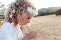 Vista lateral pequena menina loira sozinha em um campo em um dia ensolarado — Fotografia de Stock