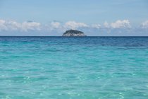 Paisaje de mar ondulado azul claro con isla rocosa en el horizonte bajo las nubes en el día soleado en Malasia - foto de stock
