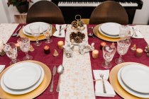 Зверху обстановка столу з окулярами та столовими приборами біля тарілок, прикрашених свічками та шишками на Різдво — стокове фото