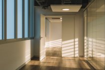 Interno di ampio corridoio soppalco vuoto con ombre geometriche e luce solare su pareti bianche — Foto stock