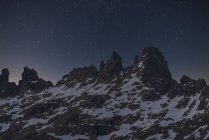 Scenic view of dark mounts with snow and rough peaks under starry sky at dusk — Stock Photo