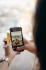 Crop anonymous female customer taking picture with mobile phone of beer and snacks in bar — Stock Photo