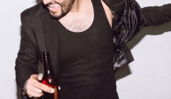 Crop alegre macho irreconhecível com olhos fechados bebendo cerveja de garrafa durante a festa contra fundo branco — Fotografia de Stock