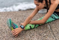 Орієнтована жінка-спортсменка виконує бокову лаунж вправи і розтягує ноги під час прогрівання під час тренувань на набережній біля моря — стокове фото