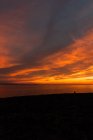 Spektakulärer Blick auf die Silhouette des Reisenden mit Blick auf das Meer vom Strand unter buntem bewölkten Himmel bei Sonnenuntergang — Stockfoto