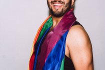 Crop méconnaissable excité barbu mâle rire avec la bouche ouverte et agitant drapeau multicolore symbole de fierté LGBTQ — Photo de stock