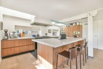 Творчий дизайн сучасної кухні між столами з посудом в світлому будинку — стокове фото