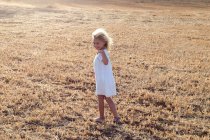 Piccola ragazza bionda da sola in un campo in una giornata di sole — Foto stock