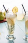 From above of cold pear cocktail in glasses with rosemary and ice cubes placed on table with fresh fruits — Stock Photo