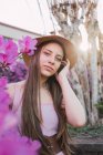 Gentle female teenager with brown hair in beads against blossoming violet flowers in city park — Stock Photo
