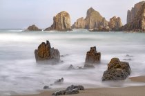 Захватывающие пейзажи с пенными морскими волнами, омывающими грубые скалистые образования различных форм на диком пляже Гейруа в Астурии, Испания — стоковое фото
