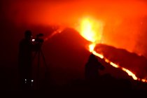 Silhuetas humanas da mídia gravando e fotografando com tripés a lava explosiva nas Ilhas Canárias de La Palma 2021 — Fotografia de Stock