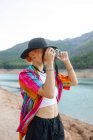 Woman with black hat in a lake taking pictures of the landscape — Stock Photo