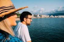 Vista laterale di coltura turista femminile contro fidanzato barbuto in occhiali contemplando oceano, mentre guardando lontano in Saint Jean de Luz Francia — Foto stock
