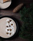 De cima de tigelas pretas com sopa de creme de castanhas colocadas em mesa de madeira com ramos verdes de abeto com cones — Fotografia de Stock