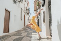 Витончена балерина стоїть на топі і піднімає ногу — стокове фото
