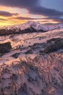 Picturesque scenery of rocky mountains covered with snow under colorful cloudy sky at sunrise — Stock Photo