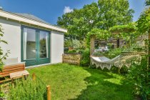 Terrasse eines Wohnhauses mit grünen Pflanzen und Hängematte unter blauem Himmel bei sonnigem Tag — Stockfoto