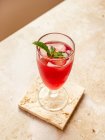 De cima de bebida vermelha refrescante saborosa com cubos de gelo e folhas de casa da moeda aromáticas no vidro na montanha-russa — Fotografia de Stock