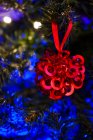 Ornement festif accroché à la branche d'un arbre de conifères décoré d'une guirlande pour la célébration de Noël — Photo de stock
