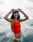 Fröhliche Teenagerin im Bikini und bauchfreiem Oberteil mit Tauchermaske blickt in die Kamera gegen stürmische See auf Teneriffa Spanien — Stockfoto