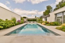 Hof einer teuren modernen Villa mit Schwimmbad und Lounge-Zone mit bequemen Sofas und Sesseln unter blauem Himmel — Stockfoto