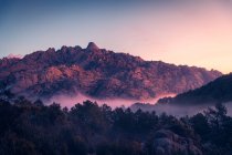 Vista panoramica di Pedriza con nebbia che si diffonde tra la catena montuosa di Guadarrama e massi con conifere all'alba in Spagna — Foto stock