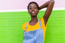 Giovane donna afroamericana in piedi su un muro colorato luminoso — Foto stock