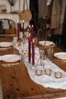 Біла скатертина і тарілки розміщені на святковому столі, прикрашені палаючими свічками і сухими гілками дерева — стокове фото