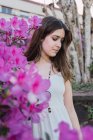 Dolce adolescente con i capelli castani in perline contro fiori viola in fiore nel parco cittadino — Foto stock