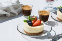 Leckere Käsekuchen mit frischen Erdbeeren und Blaubeeren unter Minzblättern gegen Espressomaschinen auf dem Tisch in der Cafeteria — Stockfoto