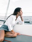 Besinnliche Teenagerin sitzt mit gekreuzten Beinen auf Bank eines Motorbootes auf dem Meer und schaut weg in Teneriffa Spanien — Stockfoto
