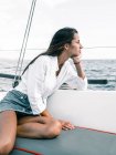 Contemplativo adolescente donna seduta con le gambe incrociate sulla panchina di motoscafo sull'oceano, mentre guardando altrove a Tenerife Spagna — Foto stock