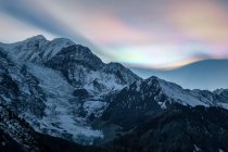 Alti ripidi pendii di montagne coperte di neve situate nella catena dell'Himalaya sotto il cielo colorato in Nepal — Foto stock