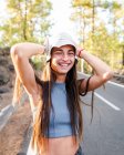 Adolescente feminina sincera com cabelos longos e mãos atrás da cabeça olhando para a câmera no dia ensolarado em Tenerife Espanha — Fotografia de Stock