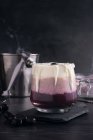 Склянка смачної бананової та чорничної смузі зі збитими вершками на рубаній дошці проти банку з йогурту та металевого відра — стокове фото