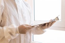 Медик-взрослый мужчина в личном защитном оборудовании, читает бумагу на планшете во время пандемии COVID 19 в больнице — стоковое фото