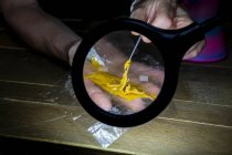 Through magnifying light view of crop unrecognizable person showing hemp glue on stick in workspace — Stock Photo