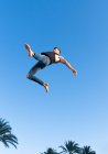 From below side view of energetic sportsman in trendy wear performing trick against blue sky in sunlight — Stock Photo